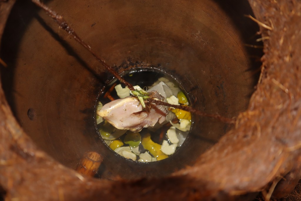 Chicken pechuga hangs inside a clay pot alongside a variety of seasonal ingredients during distillation.